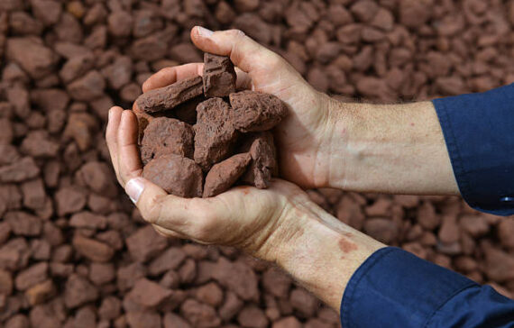 A person holding a handful of crushed iron ore close to the camera.